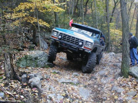 1979 Ford Bronco II - Teal Ford Bronco navigates a rocky off-road course in a forest during autumn.