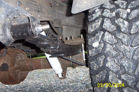 1996 Ford Bronco - Close-up of the rear suspension and tire of a lifted vehicle, showing modifications to the leaf springs and shock absorber.