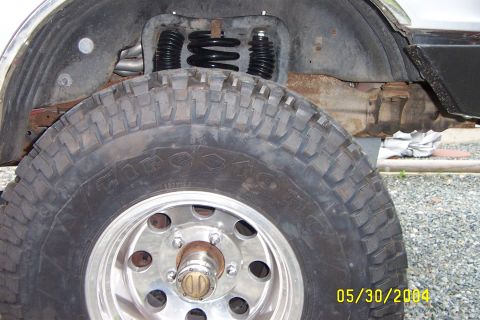 1996 Ford Bronco - Close-up of the lifted rear suspension and a large off-road tire on a vehicle.