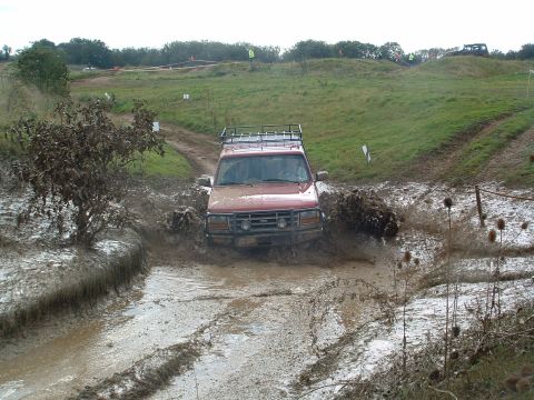 1996 Ford Bronco - This red 1995 Ford Bronco navigates a challenging mud obstacle during an off-road event.