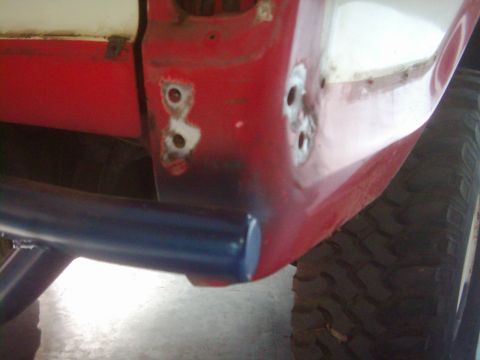 1978 Ford Bronco - Close-up of a red vehicle's body panel, showing evidence of repair work and a blue bar.