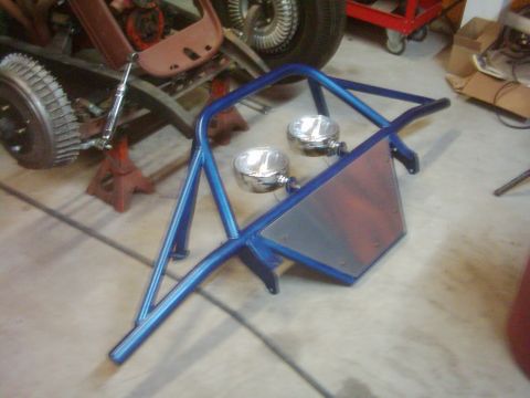 1978 Ford Bronco - A custom blue roll cage with auxiliary lights is shown in a workshop setting.
