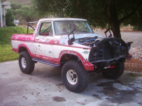 1978 Ford Bronco - This Ford Bronco is missing its front grille and bumper, and the hood is open, revealing the engine compartment.