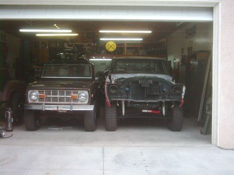 1978 Ford Bronco - A brown 1978 Ford Bronco sits in a garage next to a disassembled truck, both facing forward.