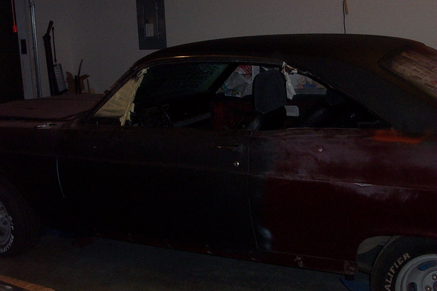 Dark maroon two-door coupe photographed from the side in a dim garage