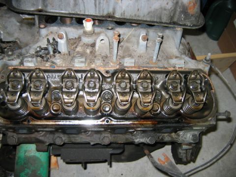 1992 Ford Bronco - Close-up of a cylinder head with the valve cover removed, showing the rocker arms, valve springs, and pushrods with visible grease, rust, a…