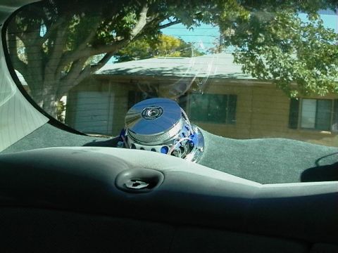 1999 Ford Taurus - A chrome and blue car stereo speaker is visible on the dashboard, with a house and tree seen through the windshield.