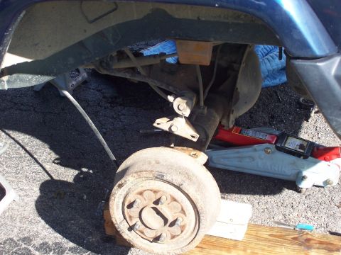2000 Jeep Cherokee - The rear suspension and axle of a blue SUV are visible, supported by jack stands.