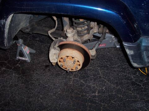 2000 Jeep Cherokee - The rear suspension and wheel hub assembly of a blue SUV are visible, supported by jack stands.