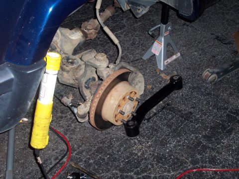 2000 Jeep Cherokee - Close-up of a vehicle's front suspension components, including a control arm and brake rotor, during a lift installation.