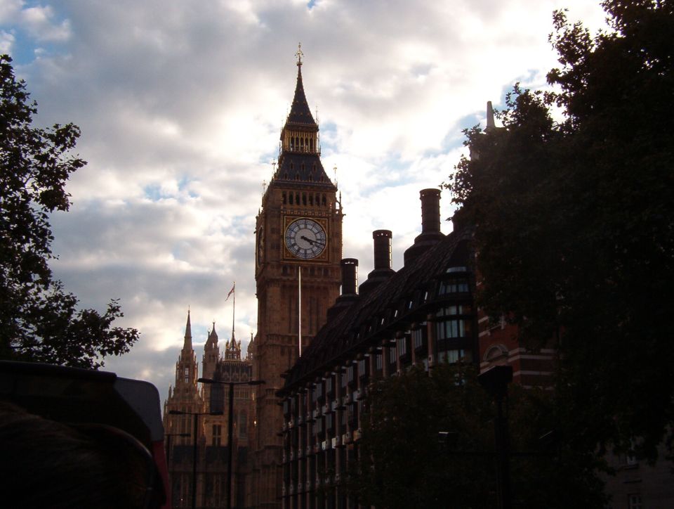 Big Ben clock tower silhouetted against a cloudy sky above London buildings