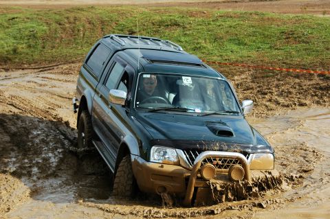 1996 Ford Bronco - This SUV is navigating a challenging muddy terrain, with its front tires deep in the mire.