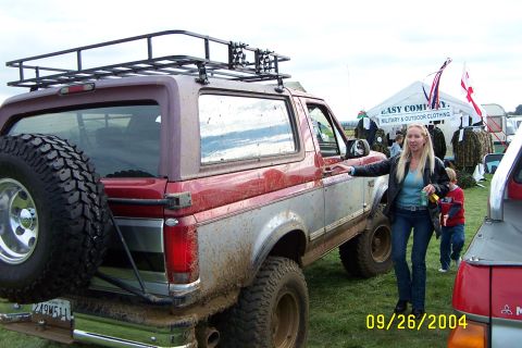 1996 Ford Bronco - A mud-covered Ford Bronco is parked on a grassy field next to a tent.