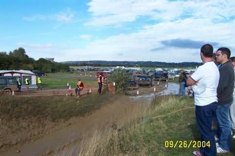 1996 Ford Bronco - An off-road event with multiple SUVs navigating a muddy track under a cloudy sky.