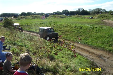 1996 Ford Bronco - Off-road vehicles navigate a grassy, hilly course under a sunny sky.