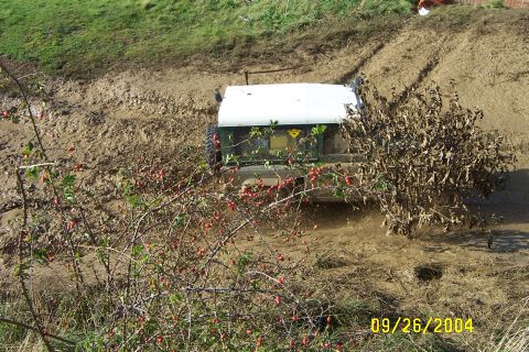 1996 Ford Bronco - An off-road vehicle struggles through a muddy terrain, its rear end visible as it churns up the dirt.
