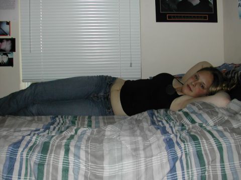 1993 Ford Bronco - Woman reclines on a bed with blinds and framed pictures on the wall behind her.