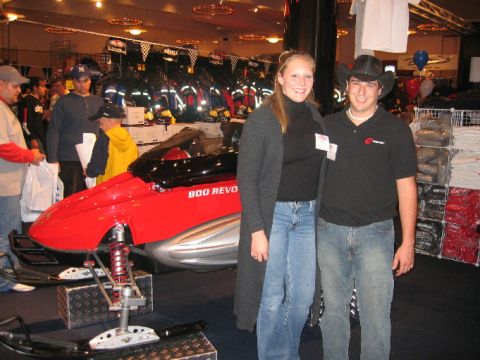 1993 Ford Bronco - A couple poses with a red snowmobile at an indoor event.
