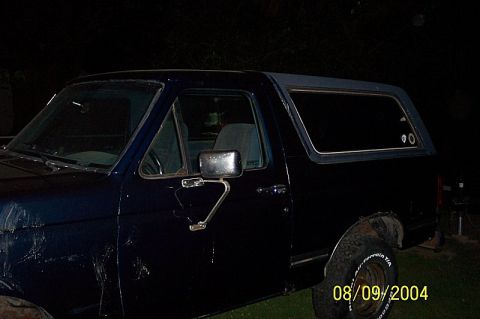 1978 Ford Bronco - A dark blue SUV is seen from the side, with a hardtop and visible tire markings.