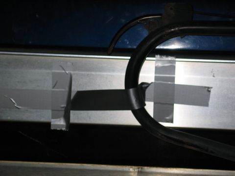 1995 Ford Bronco - A black hose is taped to a metal surface, likely a repair or modification within a vehicle's interior.