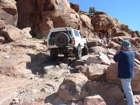 1993 Ford Bronco - White SUV navigates a challenging rocky trail with a spare tire mounted on the rear.