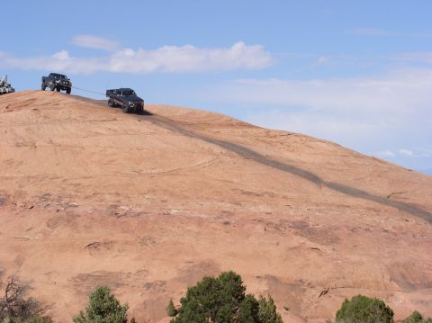 1993 Ford Bronco - Two trucks navigate a steep, rocky terrain, with one vehicle assisting the other up the incline.