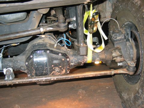 1993 Ford Bronco - Undercarriage view shows the front axle and suspension system, with a yellow strap attached to the shock.