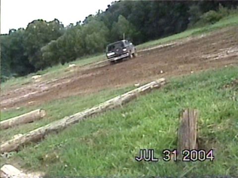 1988 Ford Bronco - A dark SUV navigates a muddy track with trees in the background, as indicated by the date watermark.