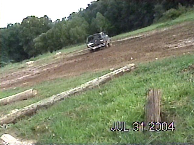 Dark SUV driving on a dirt track, rear view. Watermark reads JUL 31 2004