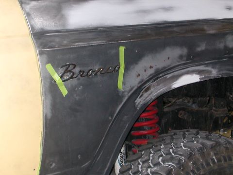 1984 Ford Bronco - The fender of a Bronco is shown with body filler and tape, indicating it's undergoing restoration work.