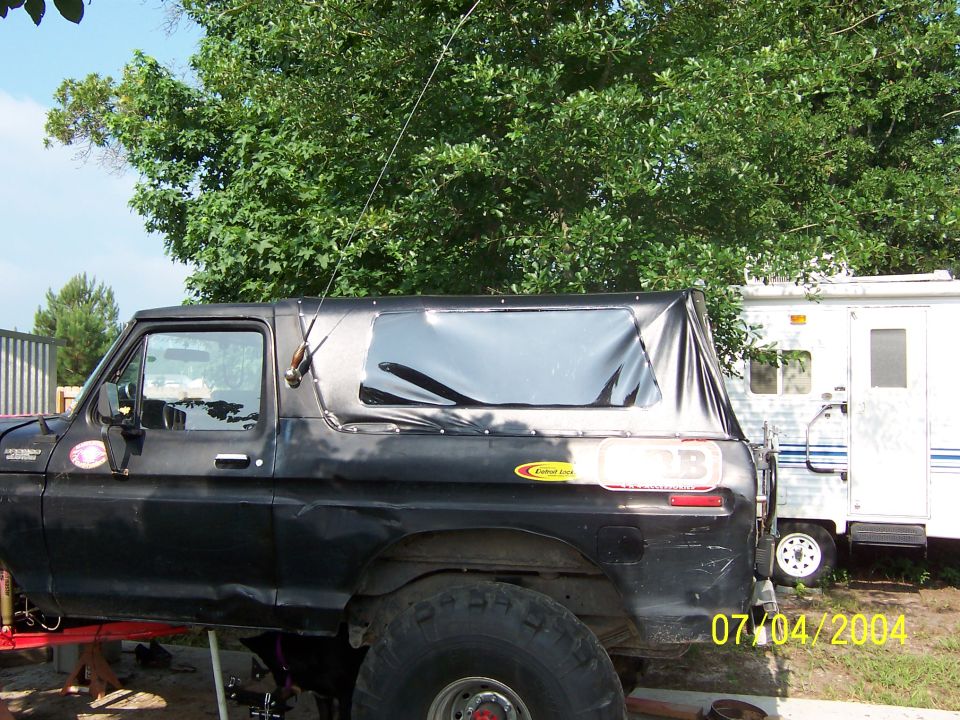 Black 1978 Ford Bronco with a soft top, parked next to a trailer