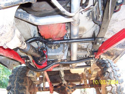 1978 Ford Bronco - Underbody view of a lifted 4x4 chassis looking up at the drivetrain, dated 10/03/2004. Visible are a red-painted transmission/transfer case…