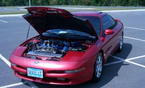1996 Ford Probe - A red 1996 Ford Probe is parked in a lot with its hood open, revealing the engine.