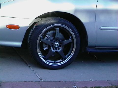 1999 Ford Taurus - A silver car's front fender and a custom five-spoke wheel are shown.