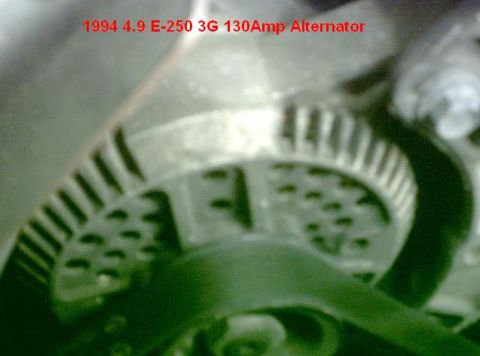 1992 Ford Bronco - Close-up engine-bay shot of a finned alternator case and its serpentine belt pulley, overlaid with red text reading "1994 4.9 E-250 3G 130A…