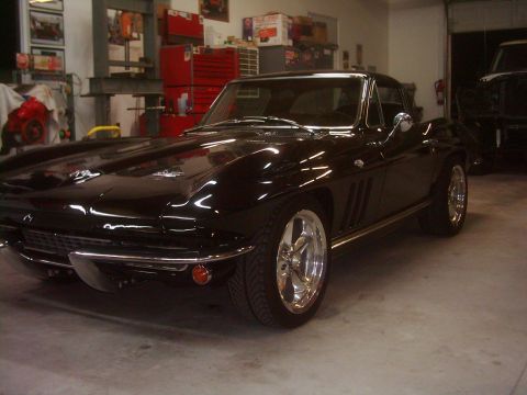1978 Ford Bronco - A black 1965 Chevrolet Corvette Sting Ray coupe is parked in a garage, with another vehicle visible in the background.
