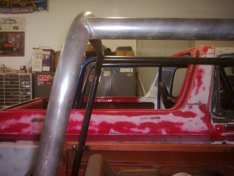 1978 Ford Bronco - Roll cage installation in progress on a red vehicle with visible bodywork and primer.