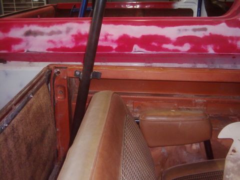 1978 Ford Bronco - The interior of a 1978 Ford Bronco shows tan seats and an orange dashboard, with a roll cage installed and red body panels ready for paint.