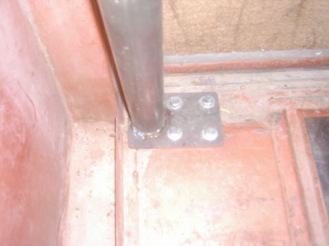 1978 Ford Bronco - A close-up view of a roll cage mounting bracket, secured with four bolts to a red interior panel.