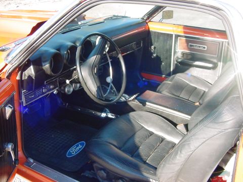 1969 Ford Ranchero - The interior of a 1969 Ford Ranchero shows black leather seats, a dashboard with gauges, and a Ford logo floor mat.