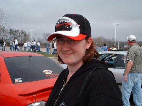 1987 Ford Bronco - A woman poses for a photo at what appears to be a car event with other people and vehicles in the background.