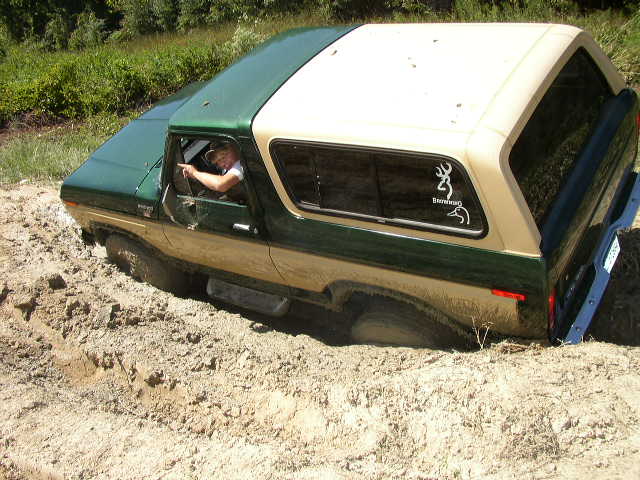 Driver points while 1978 Ford Bronco is stuck in mud