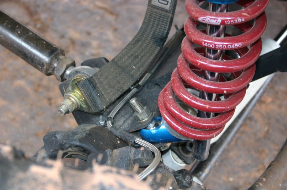 Close-up of red Eibach coilover shock and suspension linkage with a black strap