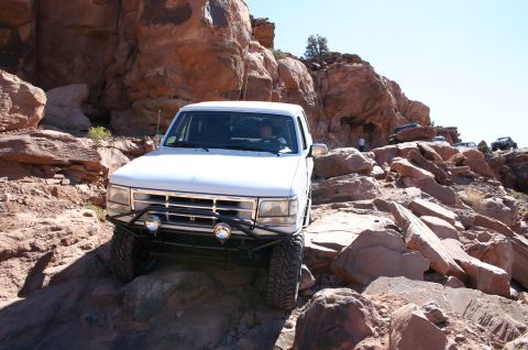 1993 Ford Bronco - This SUV is tackling a challenging off-road course with large rocks and steep inclines.