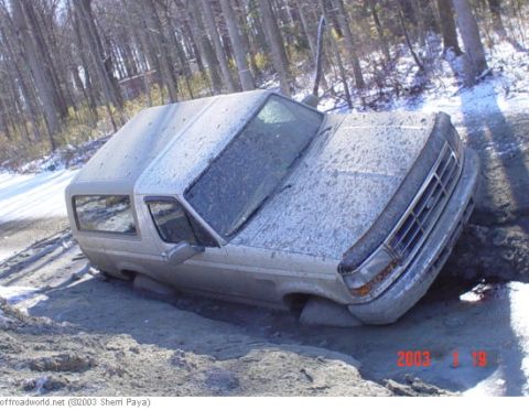 1993 Ford Bronco - A 1993 Ford Bronco is stuck in a muddy ditch with snow on the ground.