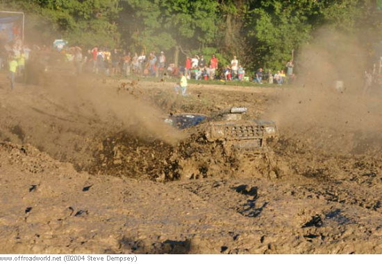 Mud bogging vehicle splashing through a deep mud pit