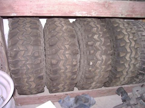 1978 Ford Bronco - Four off-road tires are stored on a wooden shelf, with the "Supermotors" logo visible at the bottom right.