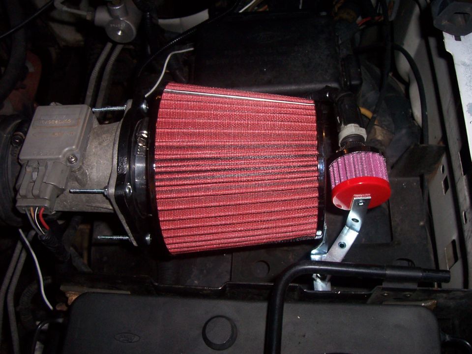 Red cone air filter clamped to mass air flow sensor in an engine bay
