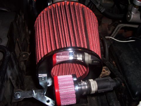 1994 Ford Bronco - Close-up of an engine's air intake system two red cone air filters and shiny metal piping.