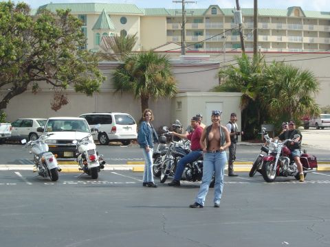 1993 Ford Bronco - A group of people and several motorcycles are gathered in a parking lot near some buildings.